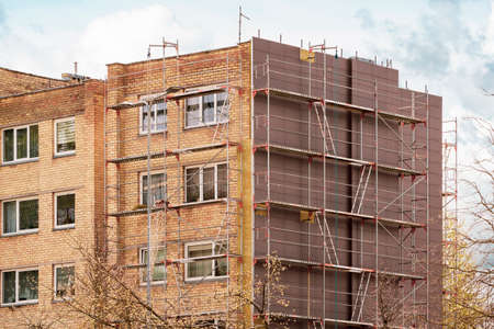 Exterior house wall renovation with mineral wool and cement tiles.Multistory house wall clad with ventilated facade cement tiles. House wall cladding technology.の写真素材