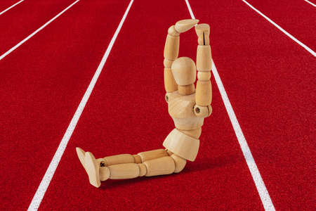 Wooden sportsman doing abs muscles situp crunches on running track.Fitness at stadium. Healthy life concept.の写真素材