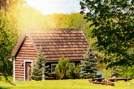 Photo of a small, wooden cabin in green forest.