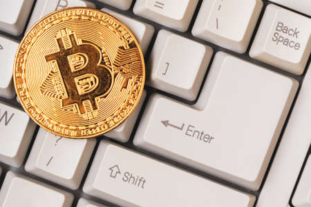 Bitcoin token coin on a computer keyboard.Crypto Currency symbol and techno gadgets.