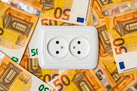 Electric socket and euro money currency. Concept of saving electricity at home. Euro banknotes....