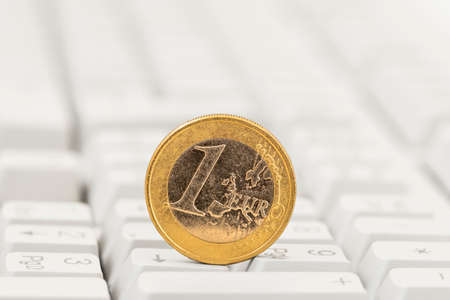 One euro coin on white computer keyboard background. Close-up view.の写真素材