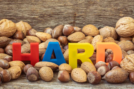 The word HARD is lined with color letters in a pile of assorted nuts. Conceptual image.の写真素材