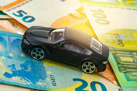 Black toy car on Euro currency banknotes. Concept of car buying, renting, service, repair and...