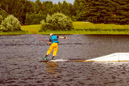 Back view of man wakeboarding on a lake. Active healthy lifestyle and watersports.の写真素材
