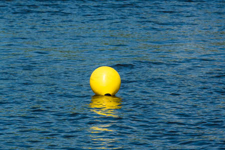 Inflatable yellow buoy in a blue water. Safety in a water.Yellow buoy ready for the race.