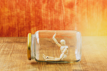 Dummy sitting alone inside glass jar. Social distance preventing infection concept.の写真素材
