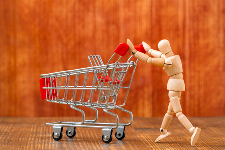 Customer with shopping cart. Let's go shopping! Wooden dummy pushing an empty shopping cart.の写真素材