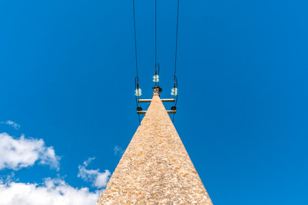 Power line post with an electric wires on sky background. Low-angle shot.