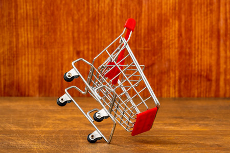 Metal mini shopping trolley falling on wooden  background. Sales concept.の写真素材