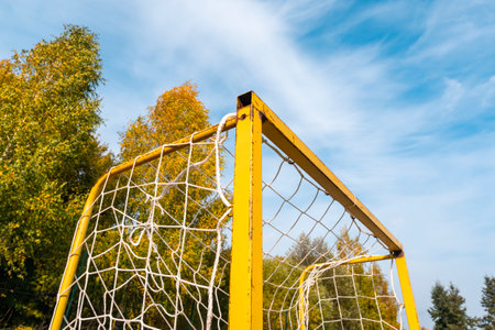 Corner of small football goal. Triangle with net of yellow goal in soccer field - close up.の写真素材