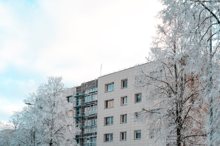 Insulation facade of multistorey residential building. Energy efficiency. Cold winter season, hoarfrost on the trees.の写真素材