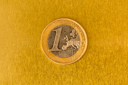 One Euro coin on the yellow shiny metal background. European currency.の写真素材