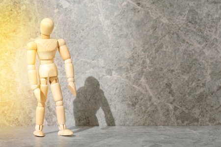 Portrait of wooden man against cement wall with sunlight and shadow. Copy space.の写真素材