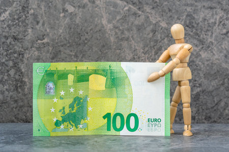 Wooden mannequin holding one hundred Euro banknote. Monetary concept.の写真素材