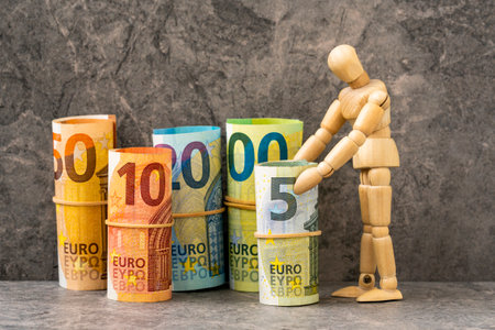 Wooden mannequin and accurately rolled hundred, fifty, twenty, ten and five paper euro banknotes. Symbol of financial prosperity, wealth, success, savings and business.の写真素材