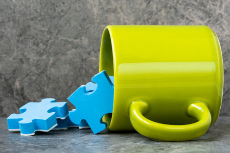 Green cup of coffee and scattered blue puzzle pieces. Creativity concept.の写真素材