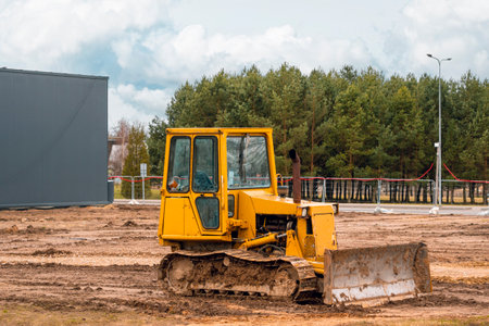 Yellow crawler bulldozer stands in the construction site. Mining machinery moving clay, smoothing gravel surface for new road. Earthmoving, excavations, digging on soilsの写真素材