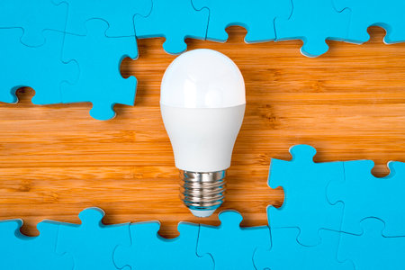 Blue puzzle frame with a bright light bulb in the middle. Concept for problem solving,solution strategy and idea.の写真素材