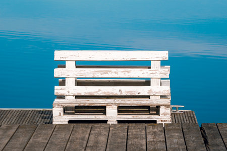 White painted wooden bench made from old pallets on a wooden jettyの写真素材