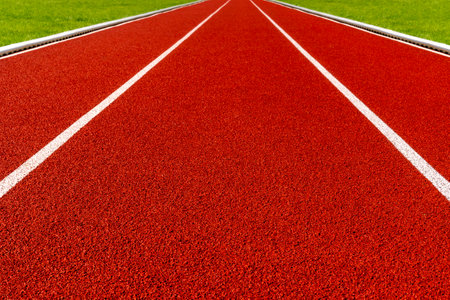 Red running track with a green grass on both sides. Concept run. Add your own motivation quote.の写真素材