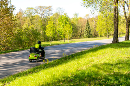 Rear view of senior man on Electric Tricycle for Mobility. Senior man driving a electric tricycle down the road on a sunny day.の写真素材