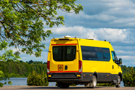 Back view of a yellow school bus standing on the parking lot with a nature landscapeの写真素材