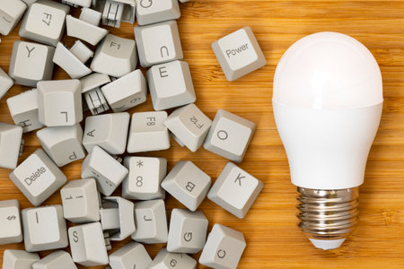 Idea and innovation concept. LED light bulb and pile of computer keyboard keys.