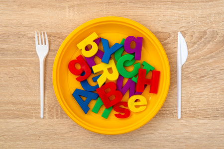 Fork, knife and plate with colored letters. Hungry for knowledge, brain feeding concept.の写真素材