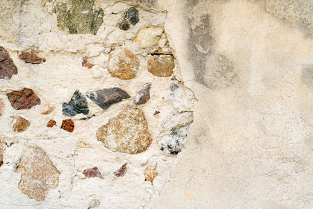 Aged stonewall material background texture. Old, worn, distressed stone wall structure with broken plaster. Copy space.の写真素材