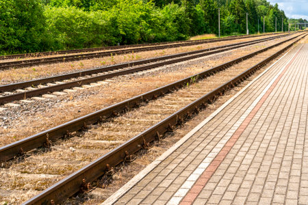 Railway platform with paving stones and empty railroad tracksの写真素材