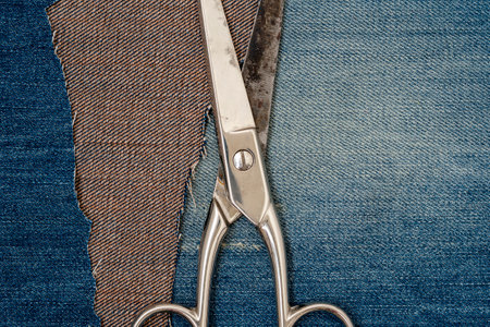 Old tailor scissors on blue jeans background.Upcycle old denim garbage. Recycling old jeans.