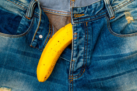 Big banana sticks out of mens jeans like mens penis as potency conceptの写真素材