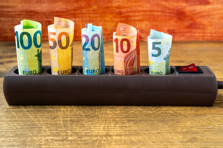 Euro banknotes inserted into an extension socket. Increasing cost of electricity for business users and residential customers. Rise in electricity prices concept.の写真素材