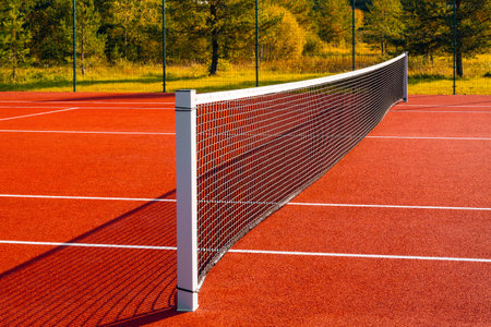 Black tennis net over a red playground outdoors.Tennis net and lines.の写真素材