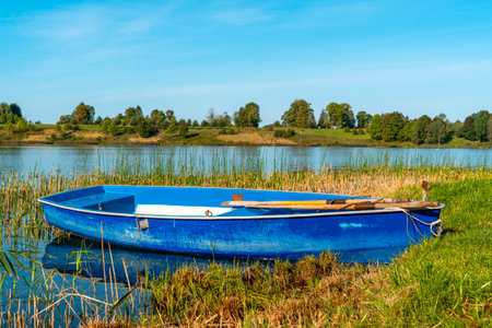 A blue wooden boat left at lake, used by local people for fishing.の写真素材