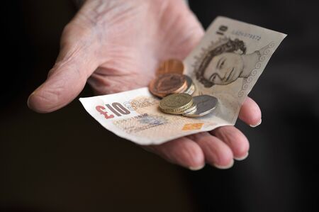 Old age pensioner holding money in the hand, UK.の写真素材
