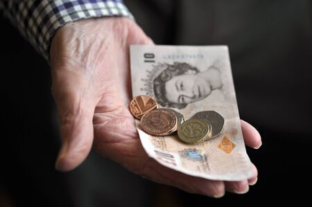 Old age pensioner holding money in the hand, UK.の写真素材