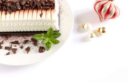 Ice-cream yule log cake with chocolate chips on a white background with Christmas decorationsの写真素材