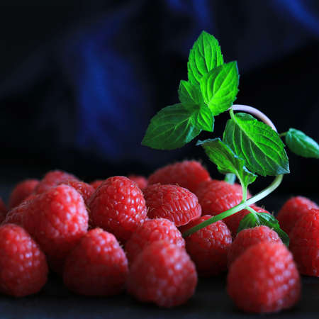 Fresh raspberries with mint leaf isolated on dark background