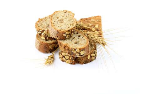 Slices of wholemeal bread with ears of wheat on a white backgroundの写真素材