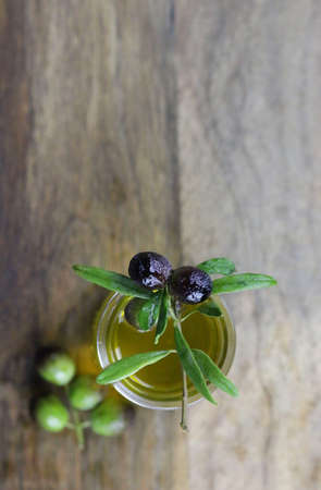Fresh olives and olive oil on wooden table