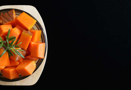 Top view of pumpkin with rosemary in a round glass plate on dark background. Raw vegetables.の写真素材