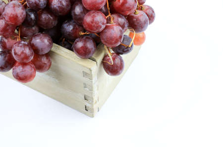 Ripe red grapes in a wooden box isolated on white backgroundの写真素材
