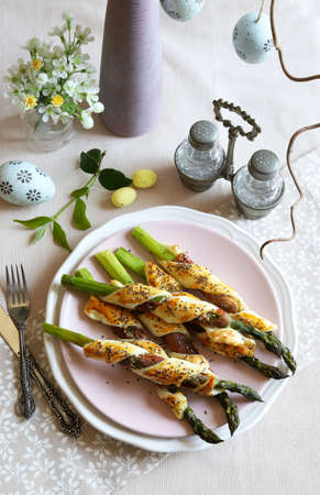 Concept of Easter table. Asparagus wrapped in prosciutto and puff pastry, decorated with poppies seeds. Easter ornaments. Top view.の写真素材