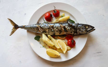 Healthy food concept, mediterranean diet. Baked mackerel with lemon, potatoes and tomatoes on white...