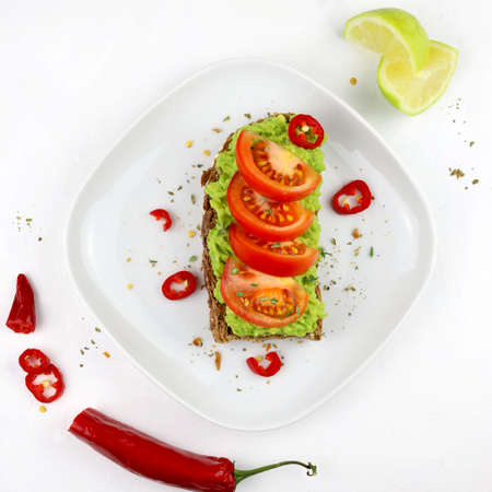 Delicious avocado toast with tomatoes and whole grain bread on white background. Healthy food concept. Top view.の写真素材