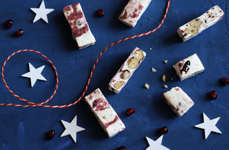 Closeup of soft nougats with berries with Christmas decorations. Blue backgroundの写真素材