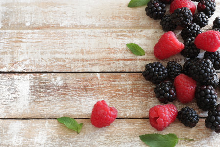 Fresh raspberries and blackberries on wooden background