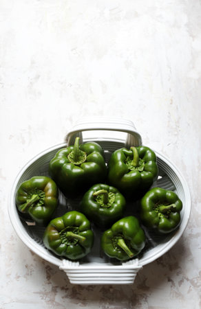 Fresh green peppers in a basket on white background. Copy space. Top view.